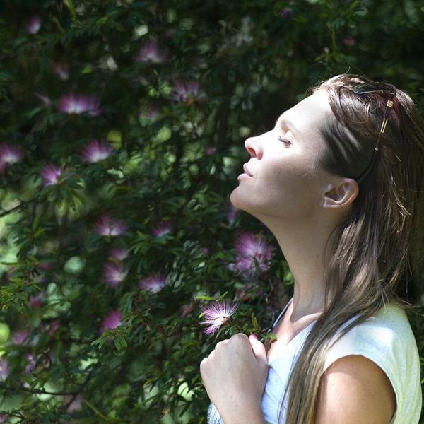 Woman smelling the air with flower around her